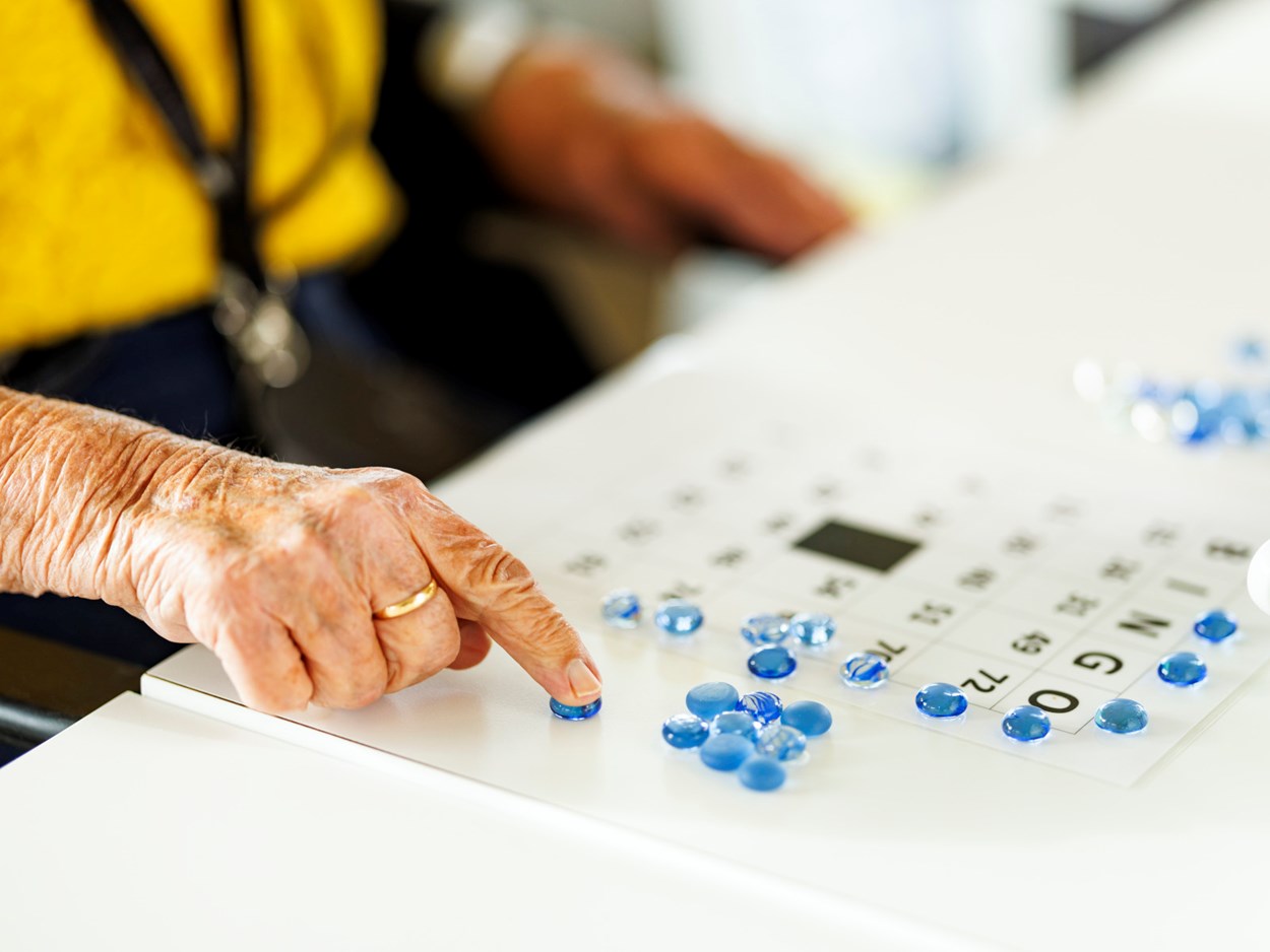 En äldre persons hand som spelar bingo.