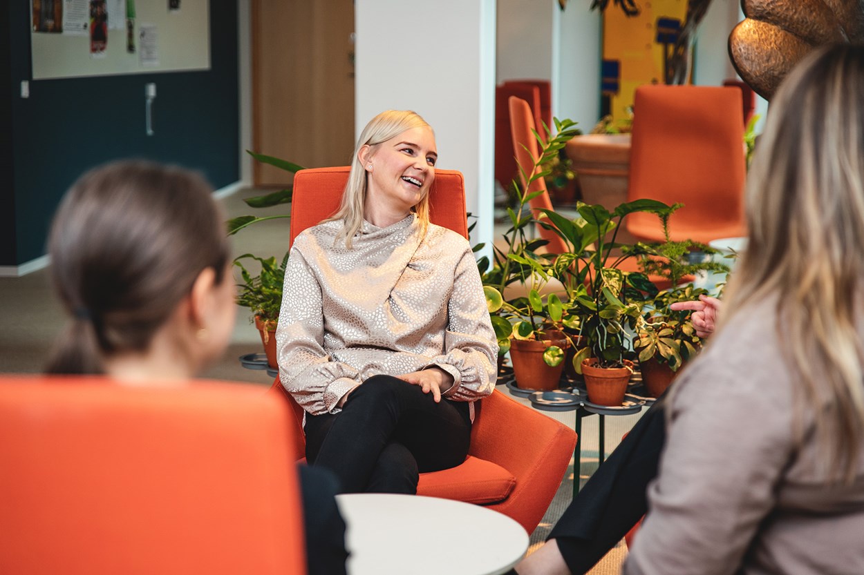 Tre kvinnor i muntert samtal i Skanska Sveriges medarbetarlounge på huvudkontoret