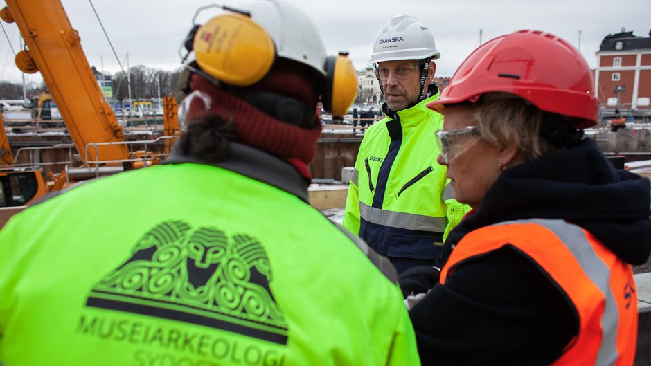 Skanskapersonal och arkeologer diskuterar. 