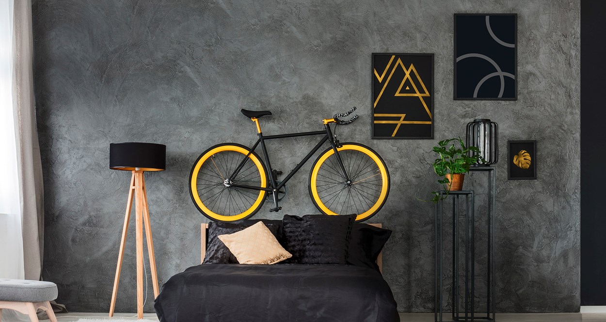 Cykel upphängd på väggen ovanför sängen i ett vardagsrum