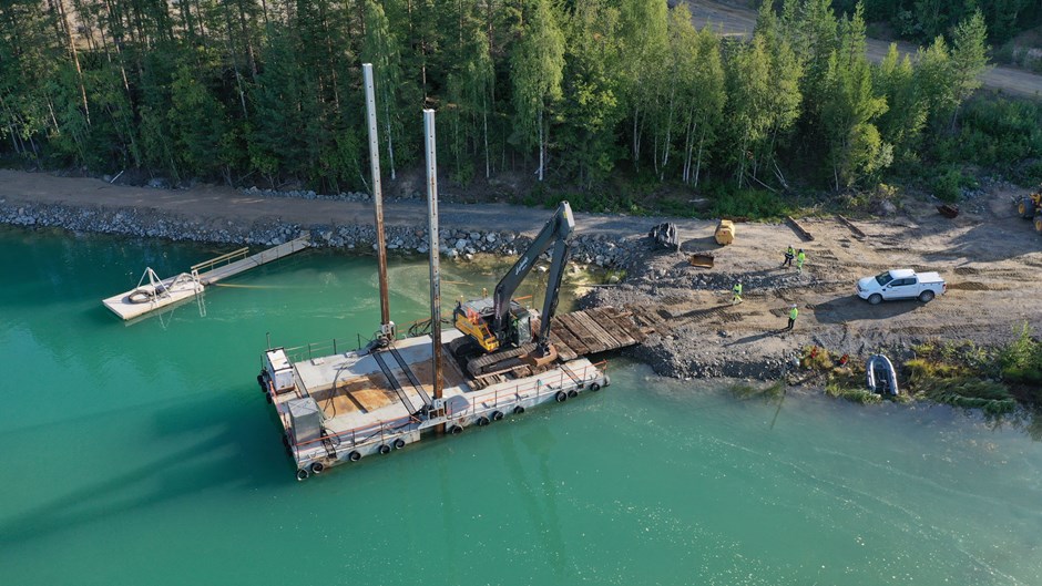 En grävmaskin arbetar ute på en flotte i Skellefteälven.