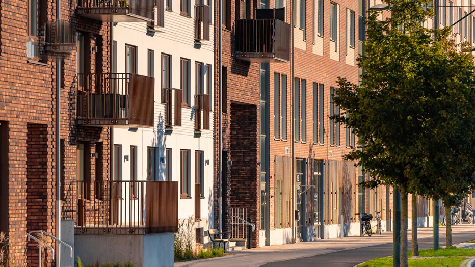 Söderfasaden längs Stora Varvsgatan i kvällssol. Närbild på den röda fasaden med portar och fönster som kvällssolen lyser upp