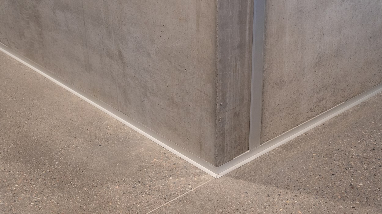 Hörn där två betongväggar möts på betonggolv.