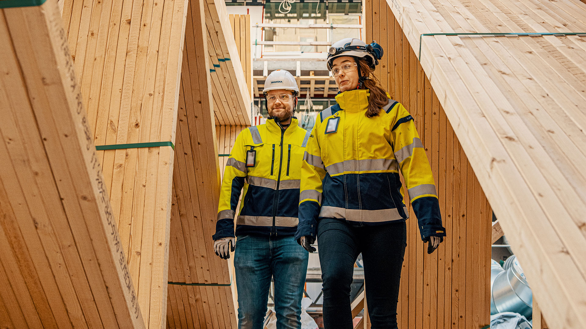 Två medarbetare med skyddskläder som går tillsammans och pratar.