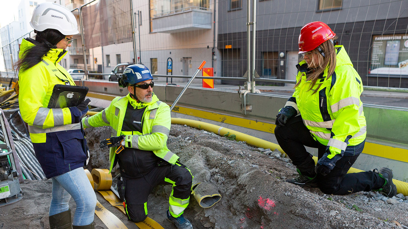 Tre personer i skyddskläder med hjälmar.