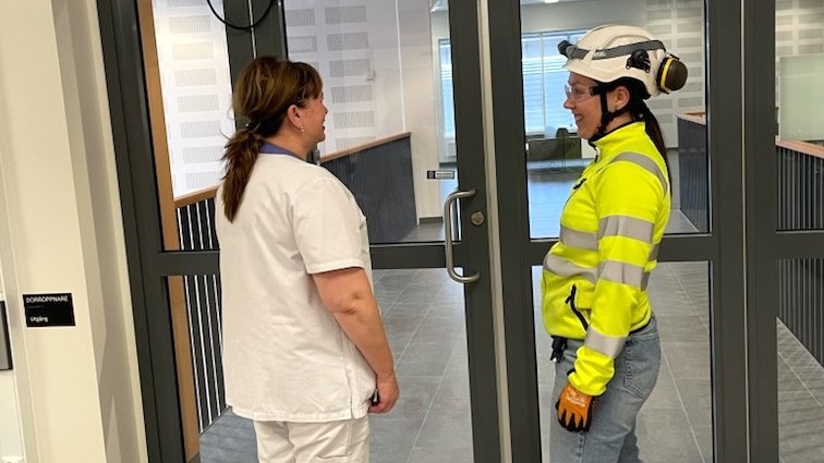 Vårdpersonal i samtal med en person som jobbar med byggprojektet. 