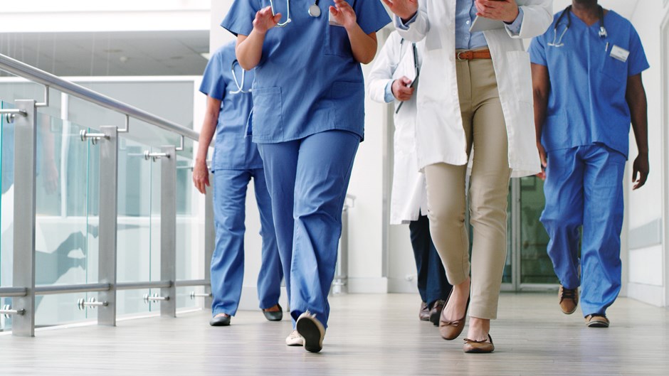 Sjukhuspersonal går i en ljus korridor.