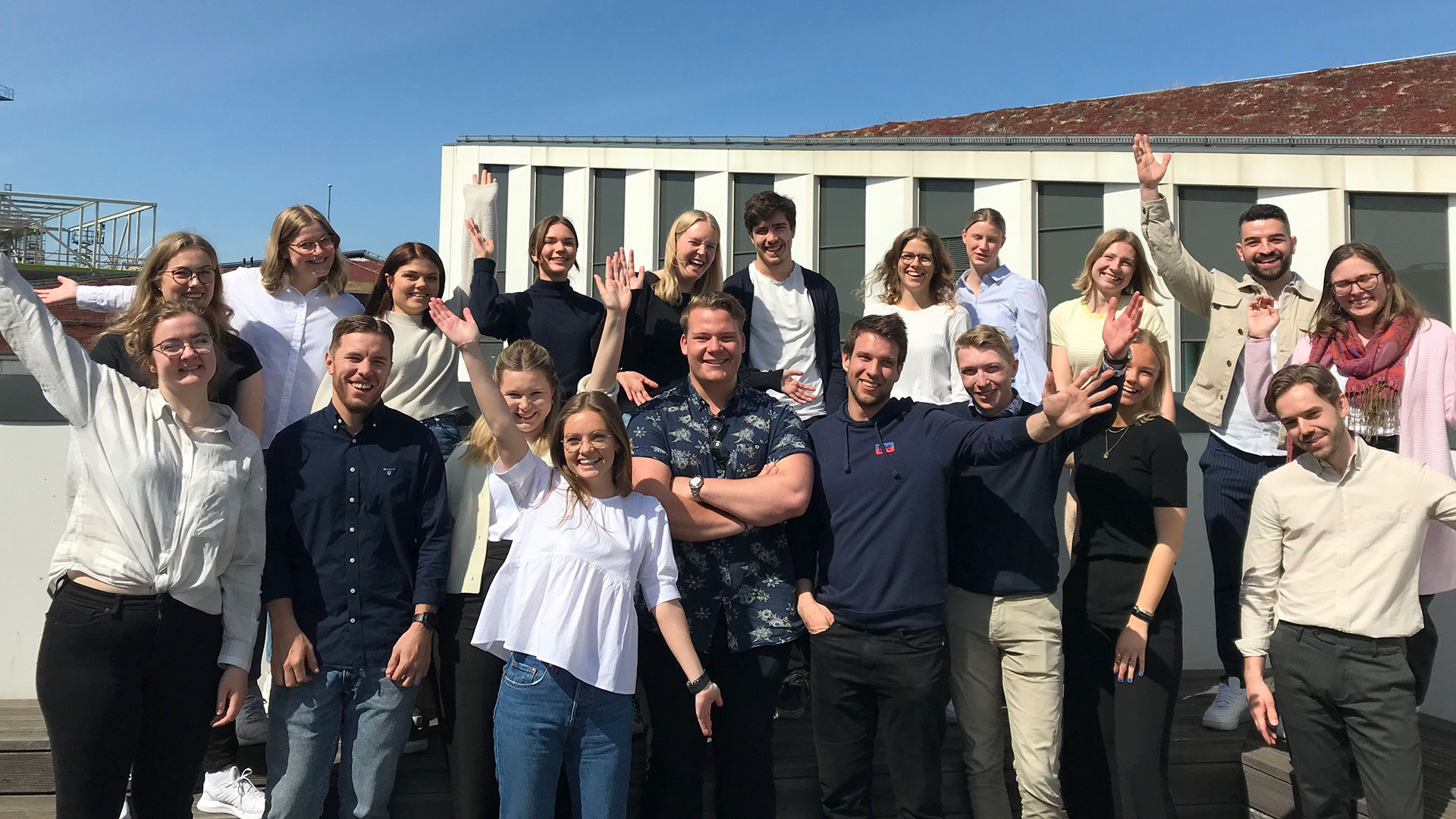 Flera glada studenter som står med händerna uppsträckta och går skanskas studentprogram.