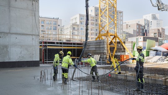 Fem byggarbetare genomför en betonggjutning.