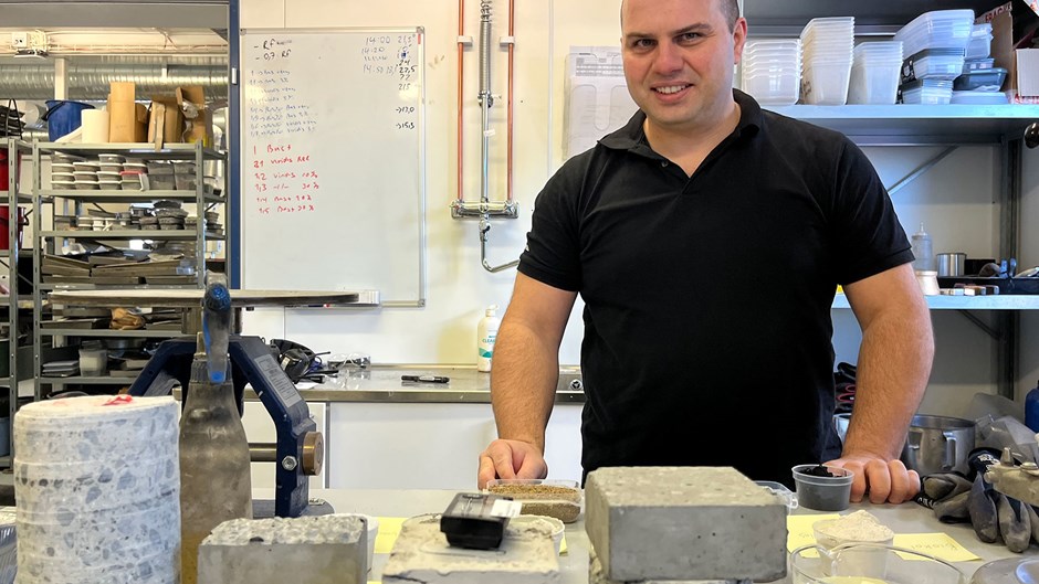 Man står i Skanskas betonglabb. Framför honom ligger fyrkantiga betongkuber från testerna av nya betongrecept.