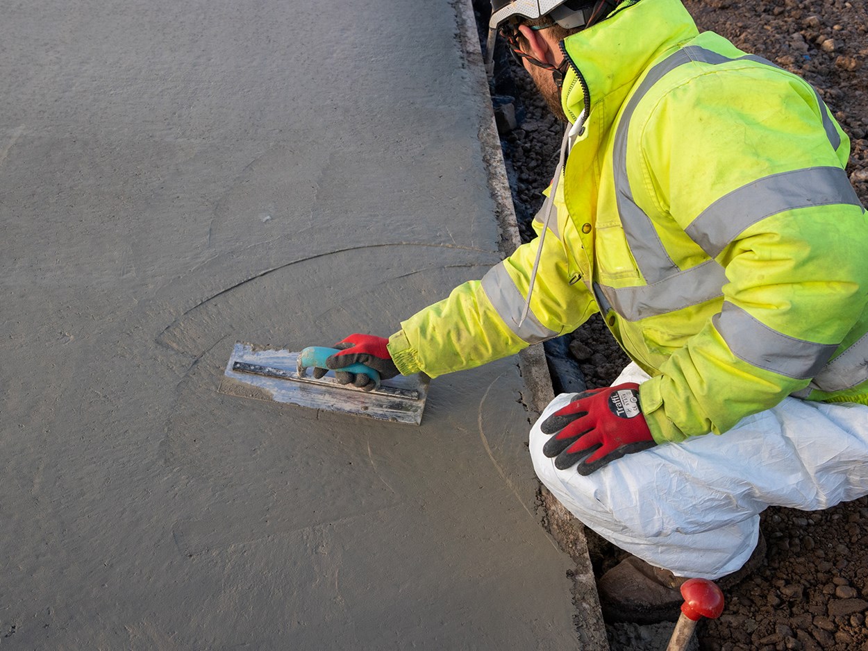 Person som sitter på huk och jämnar till en betongyta.
