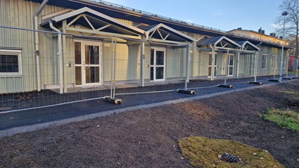 Bägersta gård förskola har en grön stående träpanel och ett mörkgrått plåttak som harmonierar fint med den naturliga omgivningen.