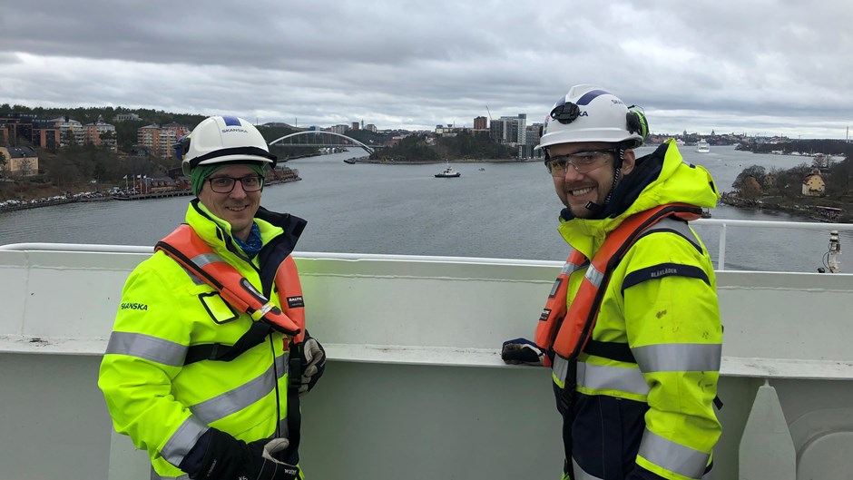 Markus och David i arbetskläder med Stockholm i bakgrunden