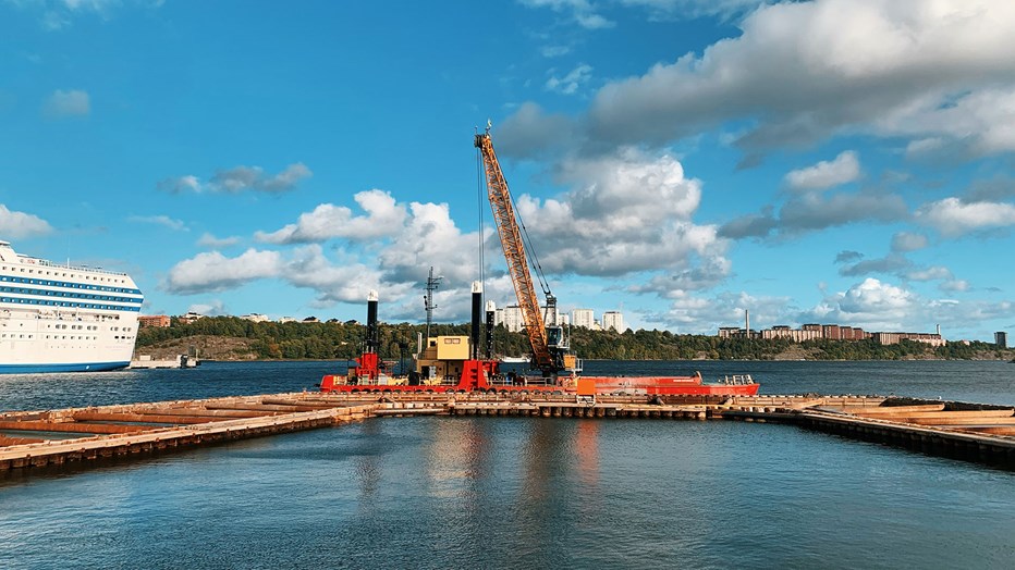 Renovering av Saltkajen och byggnation av den nya Saltpiren i Norra Djurgårdsstaden, ett stort exploateringsprojekt i Stockholm. Byggformar för pir och kaj på vattnet mot en bakgrund av land med skog och hus. Till vänster syns del av en vit passargerarfärja.