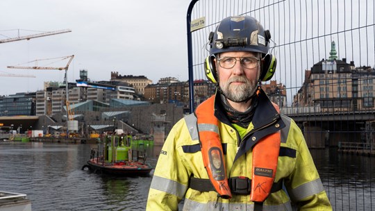 Byggarbetare står vid vattnet i Slussen i Stockholm.