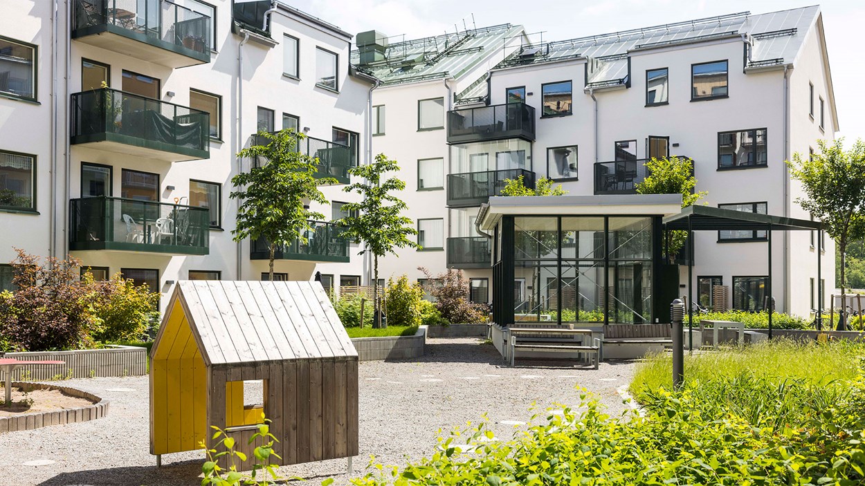Lekpark utanför ett vitt flerbostadshus i Täby Park.