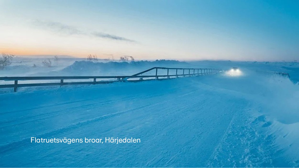Bro i vinterlandskap med en bil långt bort omgiven av snörök.