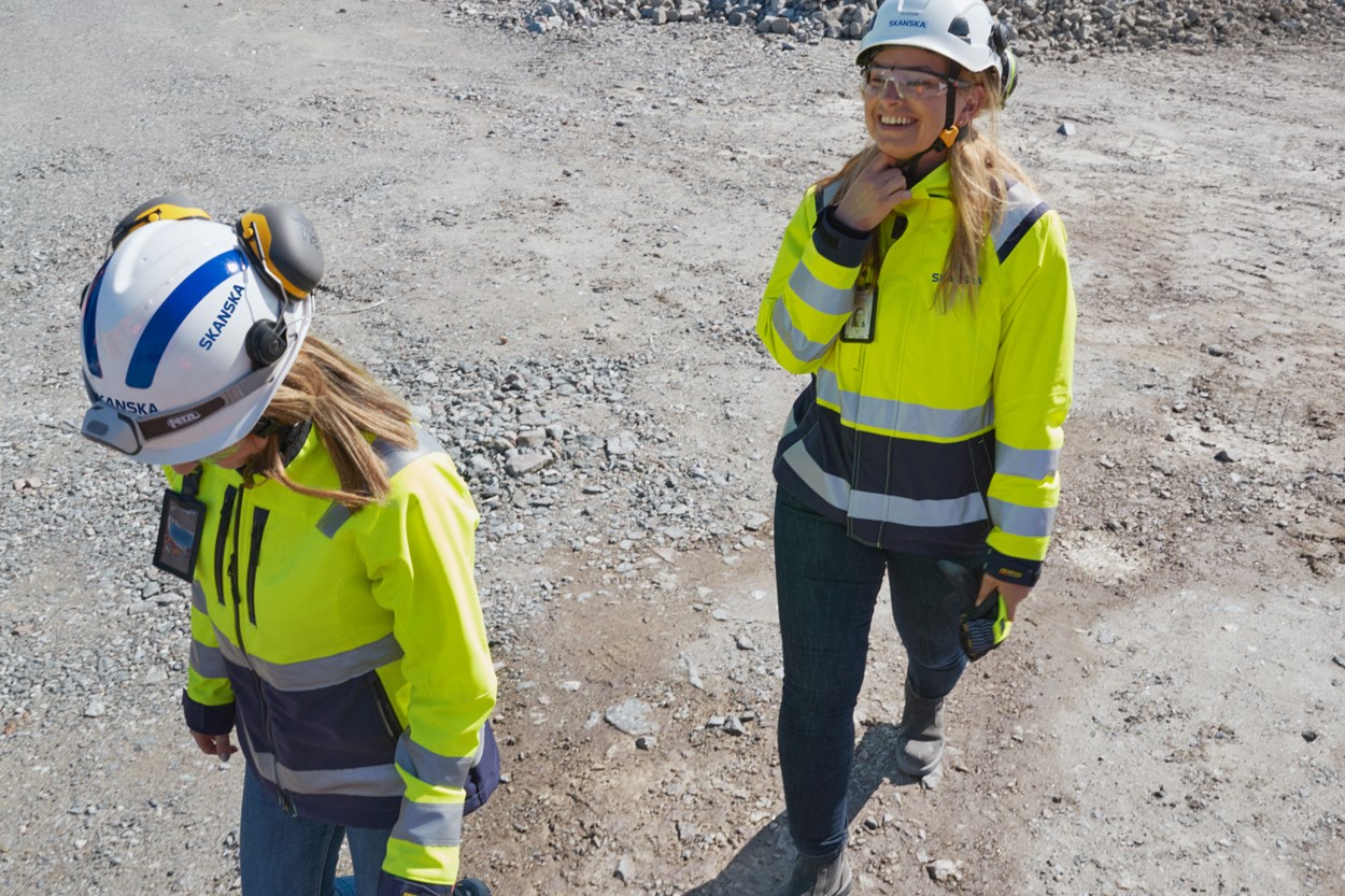  Två kvinnliga produktionsingenjörer går skrattande tillsammans på arbetsplatsen