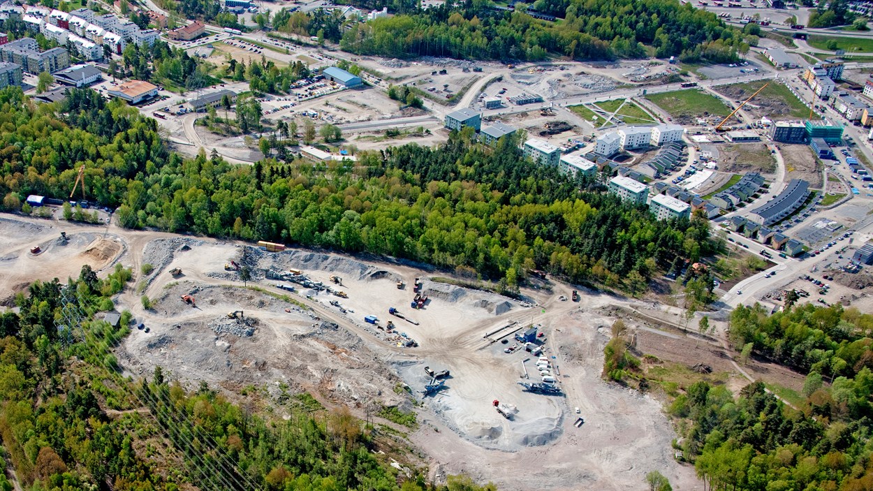 Vy ovanifrån över en täkt, skog och hus.