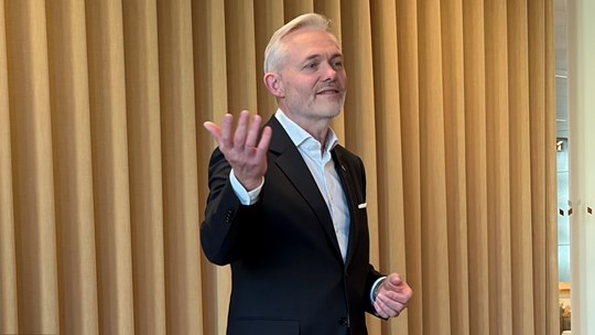 Man i kostym står på scen och talar.