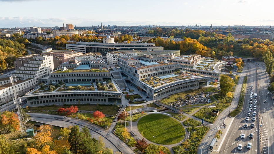 Campus Albano – en ny samlingspunkt för Stockholms studenter. I samverkan med Akademiska Hus skapade vi 65 000 kvm utbildningslokaler med fokus på lärande, hållbarhet och biologisk mångfald. Foto Anders Bobert Drönarvy över campusbyggnader och gröna ytor med intilliggande vägar.