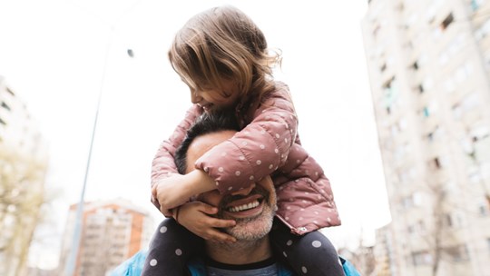 En pappa har sin dotter på axlarna.