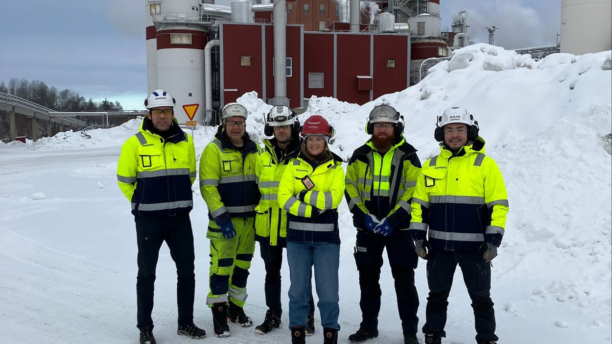 Gruppbild människor i varselkläder i ett snöigt industriområde 