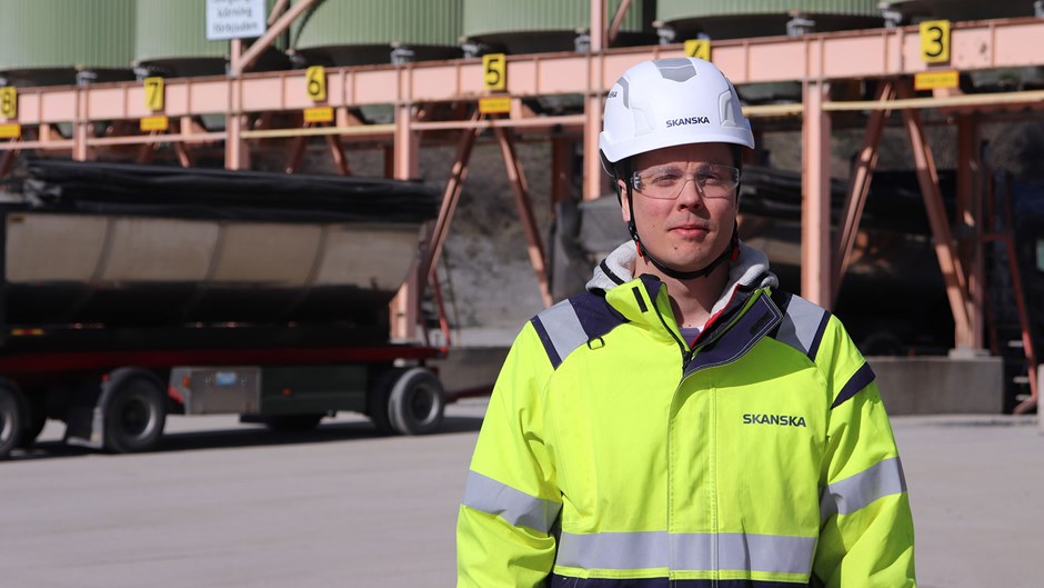 Bild på Christopher Elofsson Hakola som står framför asfaltverket i neonfärgad skyddsutrustning.