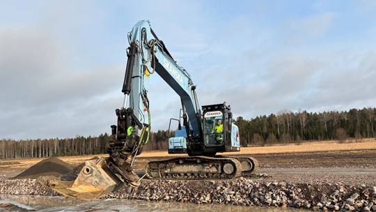 : En maskinförare från Skanska sitter i hytten på en eldriven grävmaskin.