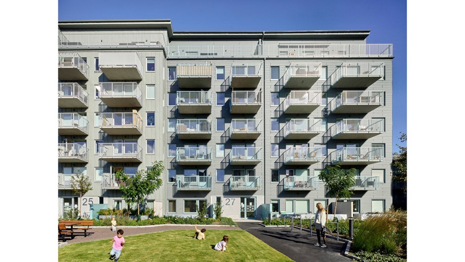 Barn leker på en gräsmatta omgärdade av höga flerfamiljshus.