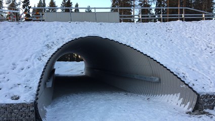 En av skidportarna (en rörbro) med gabioner på sidan och tillhörande elljusspår. Upptill ser  man vägräcket som monteras.