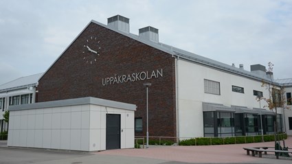 Skolans fasader består av vitpigmenterade betongelement och gavlarna är klädda med tegel.