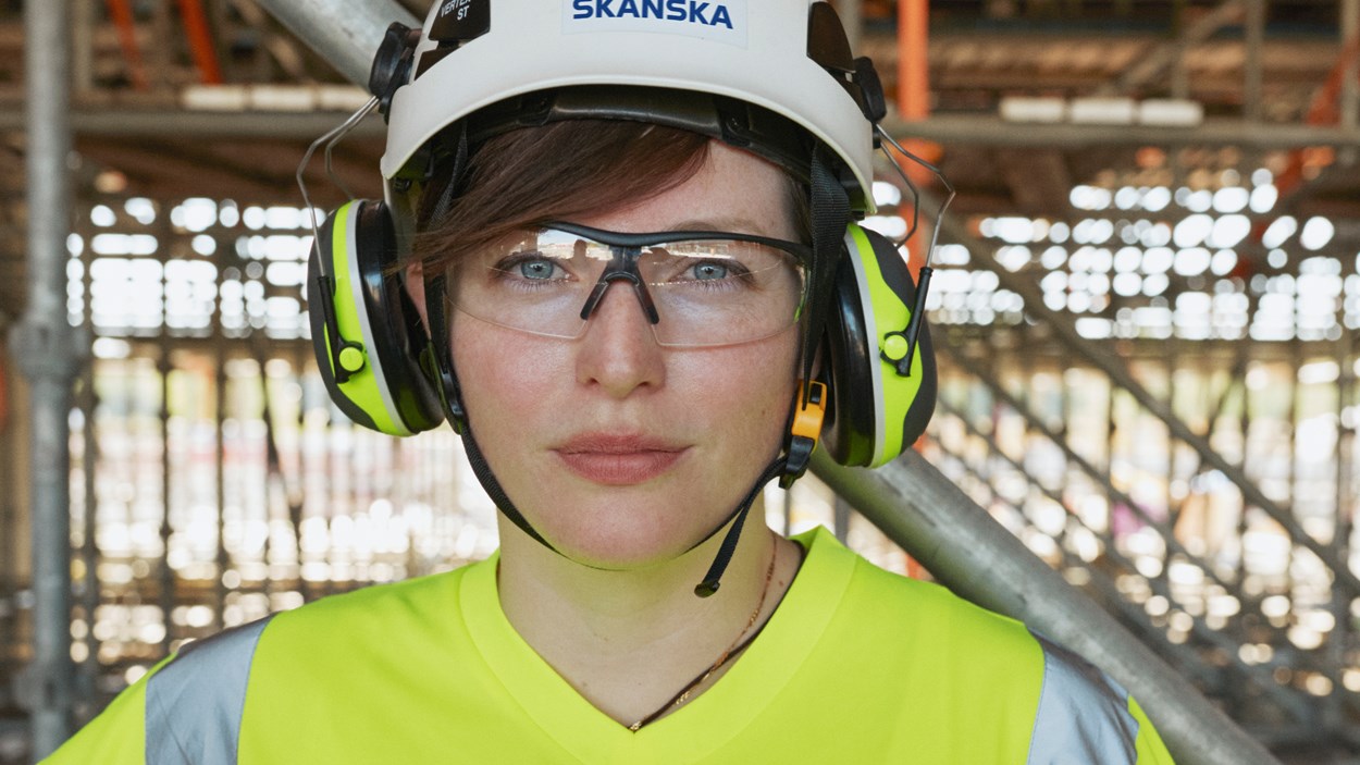 Ansiktet på en kvinna med bygghjälm och skyddsglasögen.