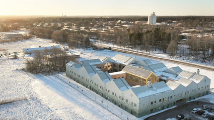 Byggnaden har ett varierat taklandskap och en mönstrad fasad i mjuka grästoner.