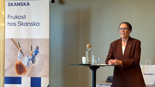 Kvinna står framför ett draperi och talar.
