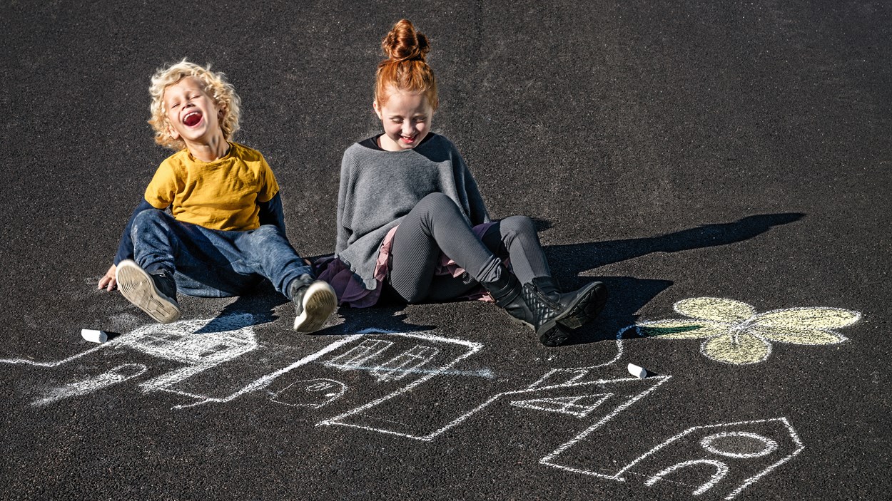 Children painting with crayons on asphalt
