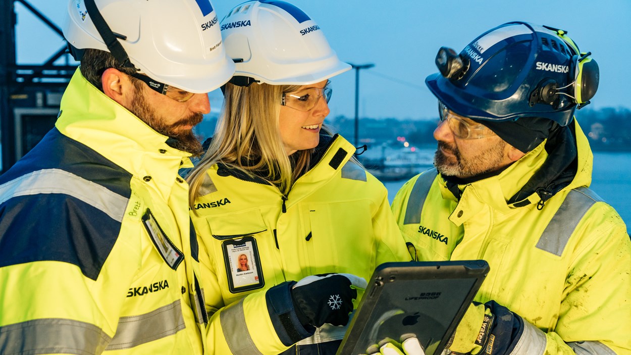 Collegues with helmets looking at an iPad