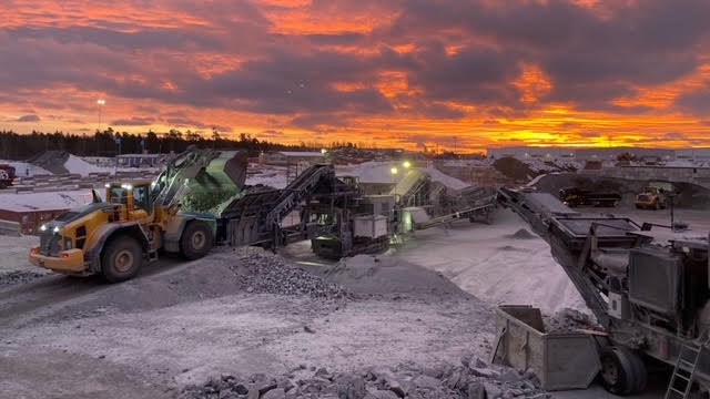 Lastbilar, maskiner och stora högar med bergmaterial på Skanskas krossanläggning i Jordbro.