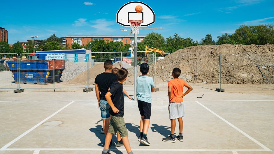 Barn som spelar basket på den nya aktivitetsplatsen med basketplan.