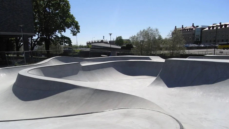 Skejtpark i grå betong med böljande runda former.