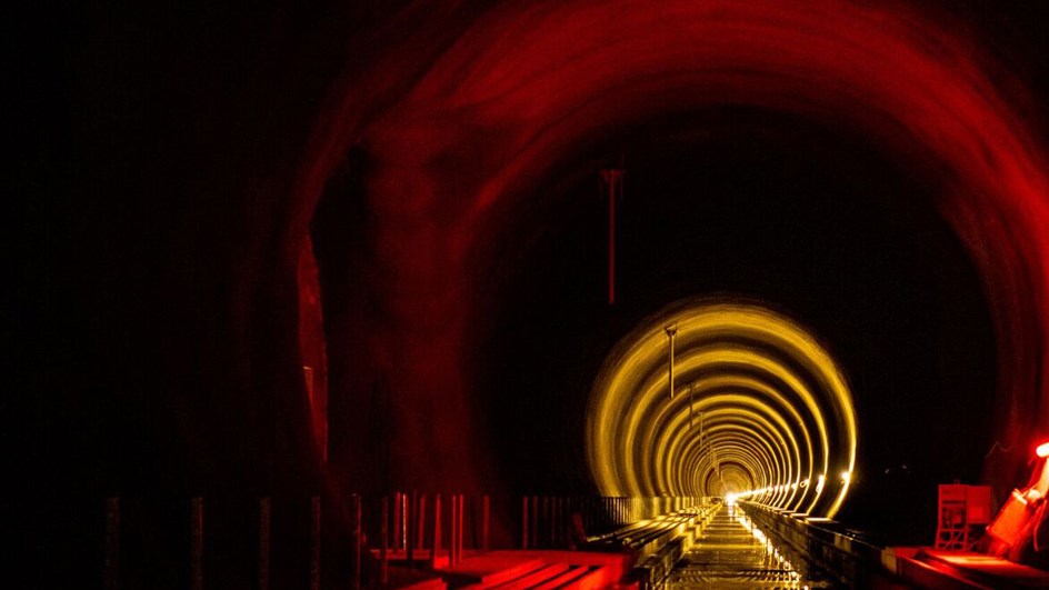 Rött ljus inuti en tunnel som lyser upp väggar och tak.
