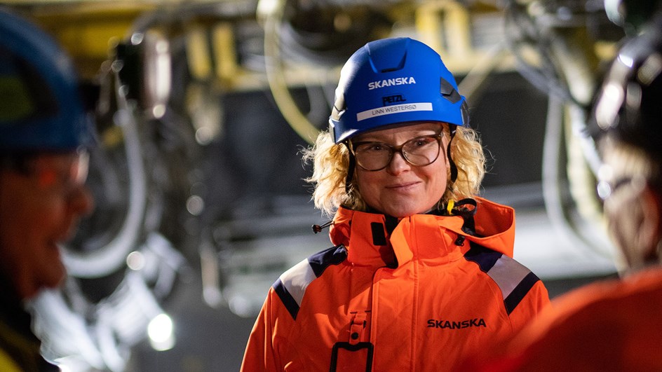 Kvinnor i varselkläder och hjälmar under samtal i en tunnel.