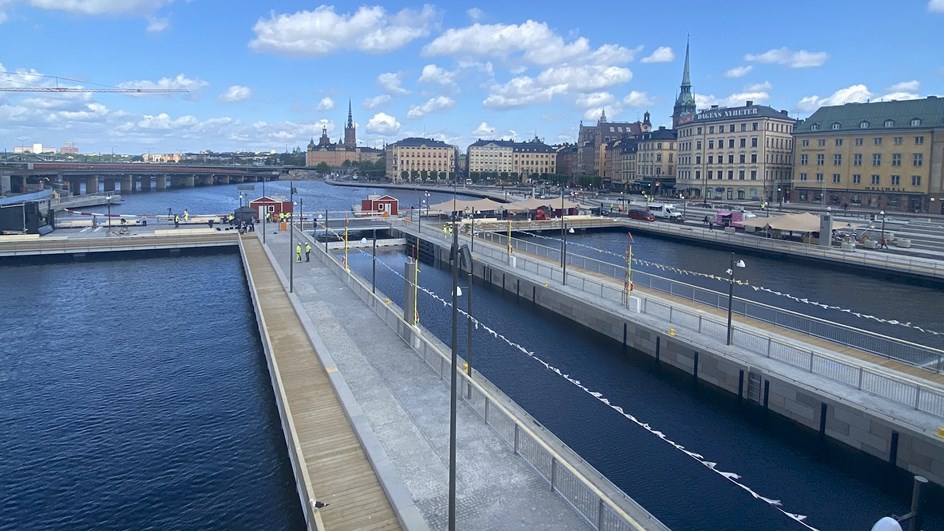 Låga broar över vattnet, i bakgrunden syns stadens siluett med olika byggnader.