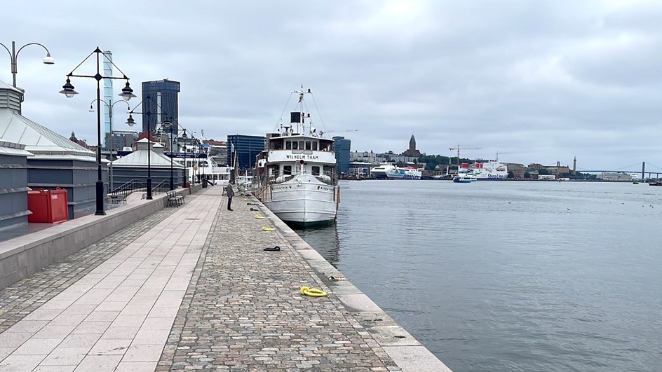 Stenbelagd bred kaj med båtar som ligger intill.