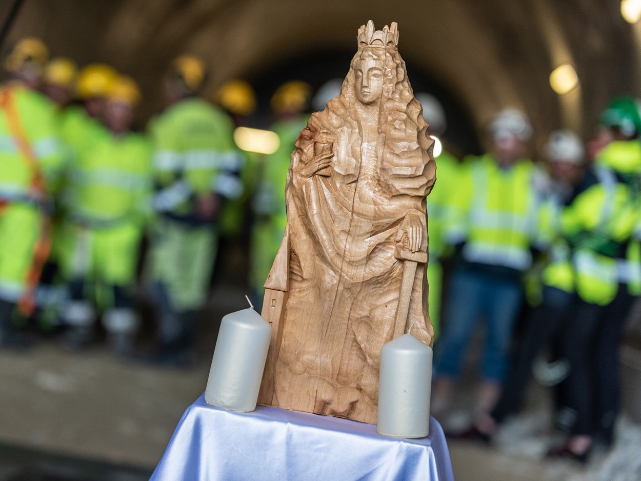Helognfigur i förgruend men gruvarbetare i varselkläder i bakgrunden.