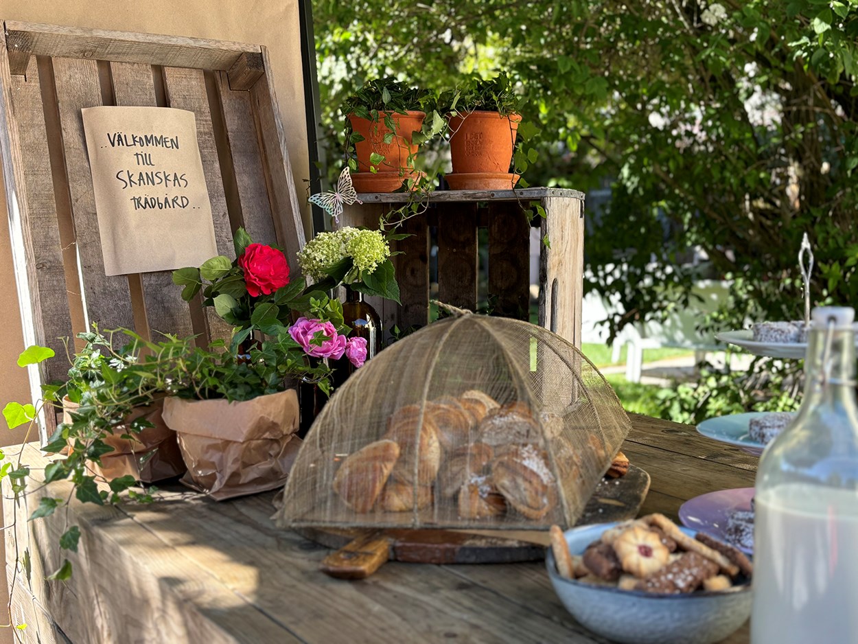 Bullar i och kakor i brödkort på trälår med blomkrukor i bakgrunden