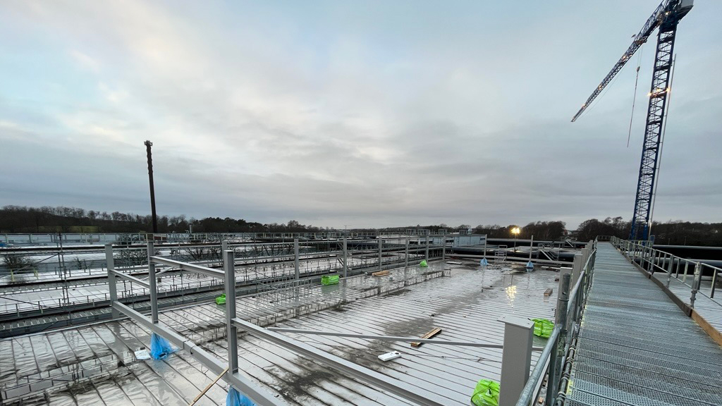 Takarbete med ställningar och säkerhetsräcken under grå himmel.