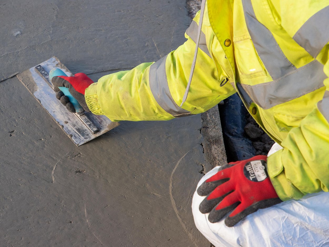 Person som sitter på huk och jämnar till en betongyta.