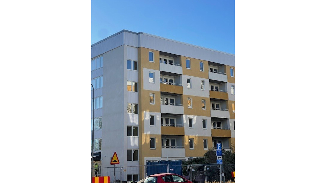 Flerbostadshus i Farsta strand med ljusgul och vit fasad samt balkonger, en av byggnaderna i Edö seniorbostäder som renoverats för ökad tillgänglighet.