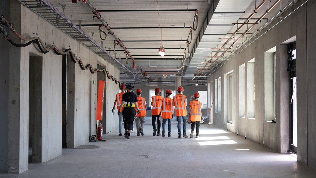 Elever med besöksvästar i en korridor på en byggarbetsplats.
